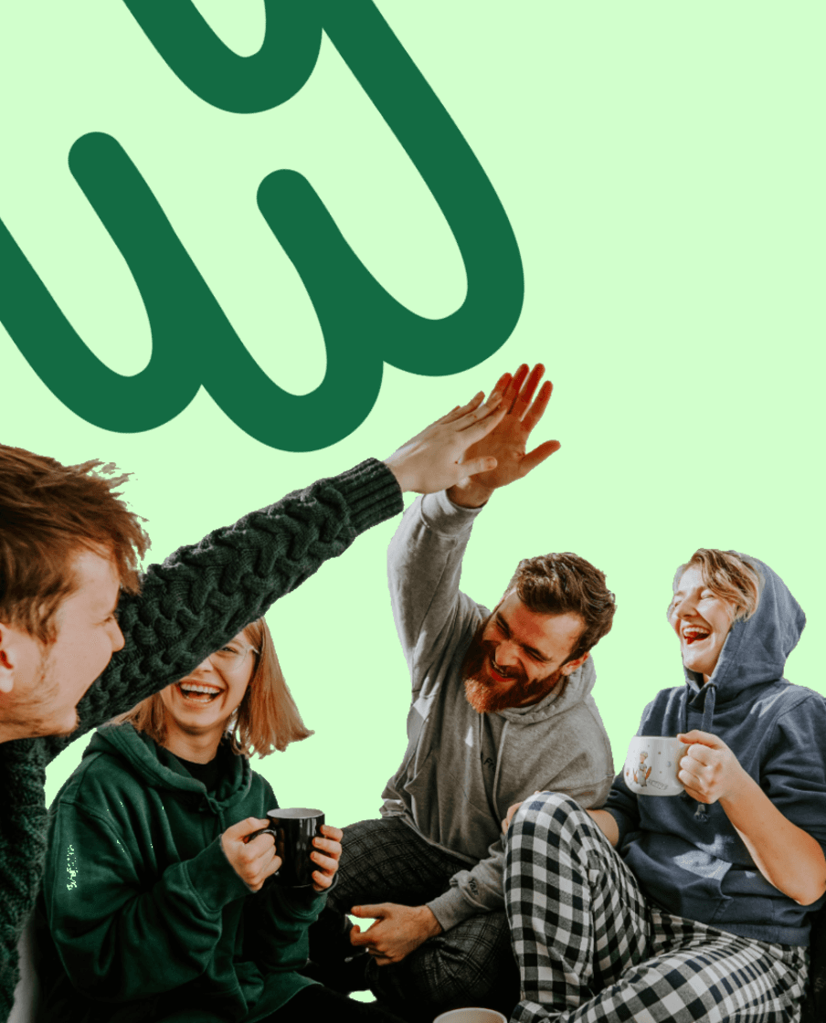 Vier junge Leute sitzen zusammen, lachen und geben sich ein High five